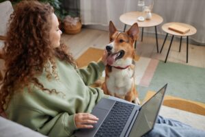 Compare-Pet-Insurance-woman-using-her laptop-and-playing-with-her-dog